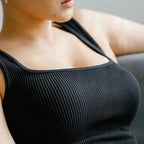 Lady wearing a black ribbed tank top against a neutral background