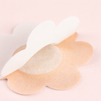 Close up of the back of the disposable nipple covers showing adhesive on a light pink background
