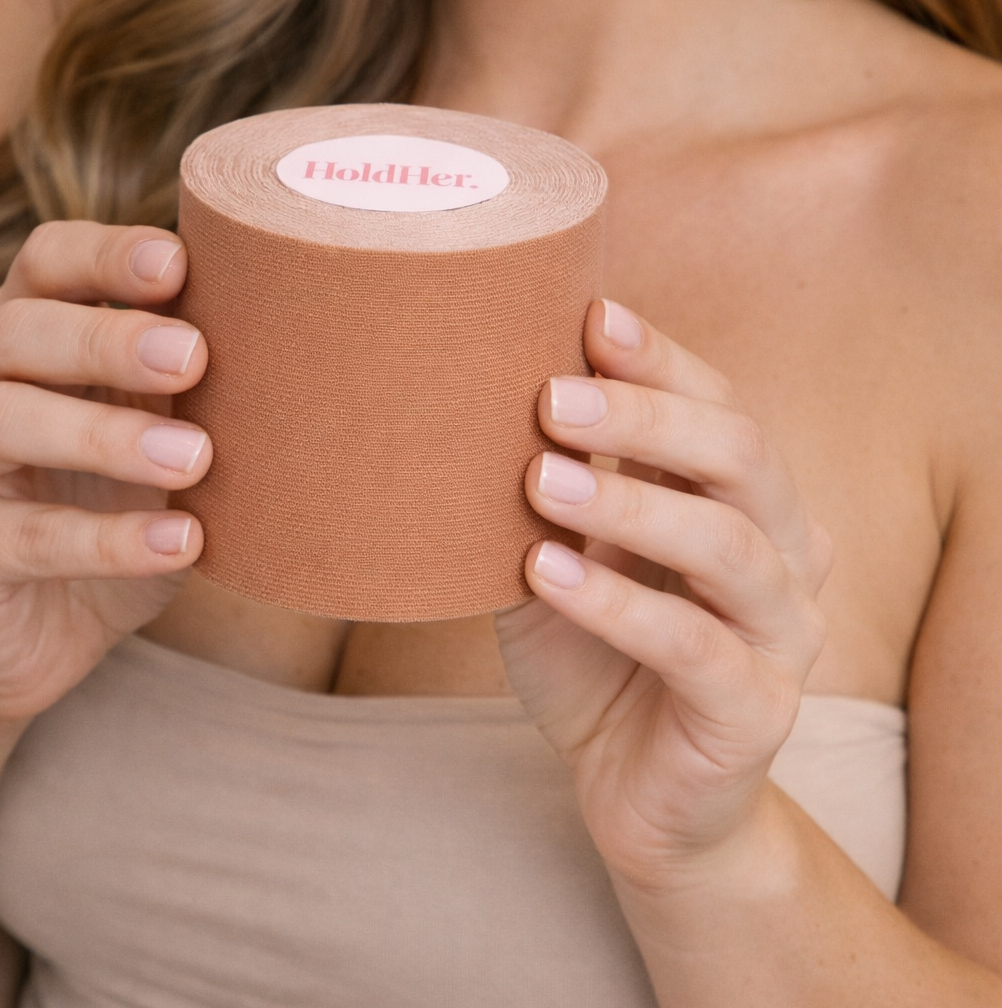 Person holding a roll of boob tape with 'HoldHer' branding.